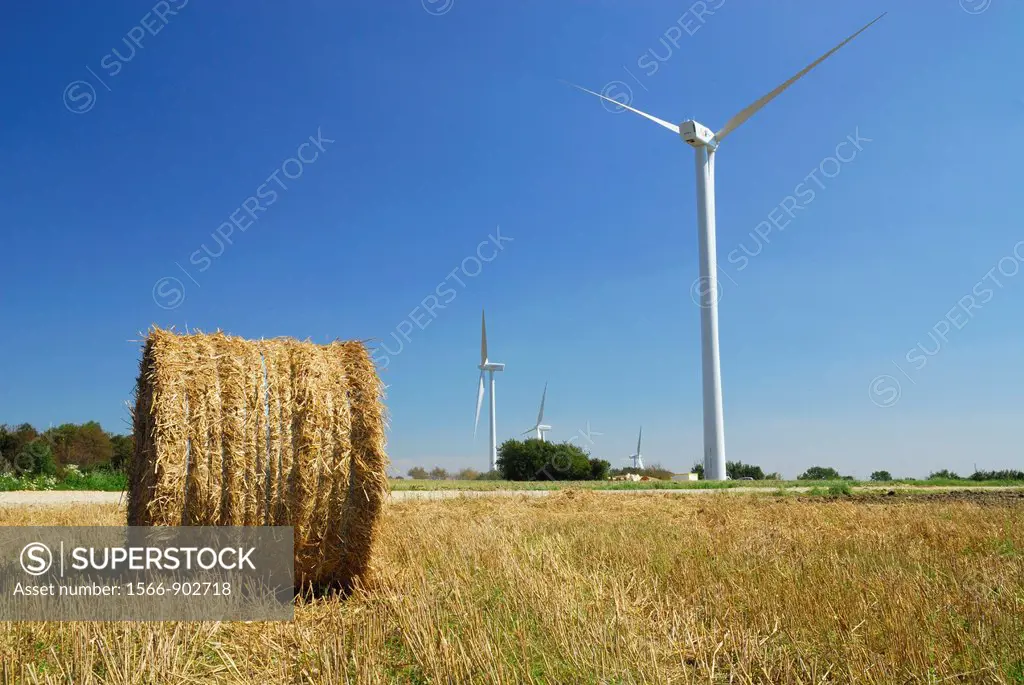 Wind turbine in an harvest meadow with hay bales, Lorraine region, France