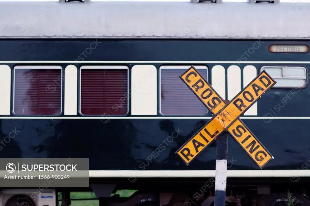 Rovos Rail passenger train waggon, passing a railroad crossing with the coresponding street sign formed as an ´X´ saying ´Railroad Crossing´, Botswana...