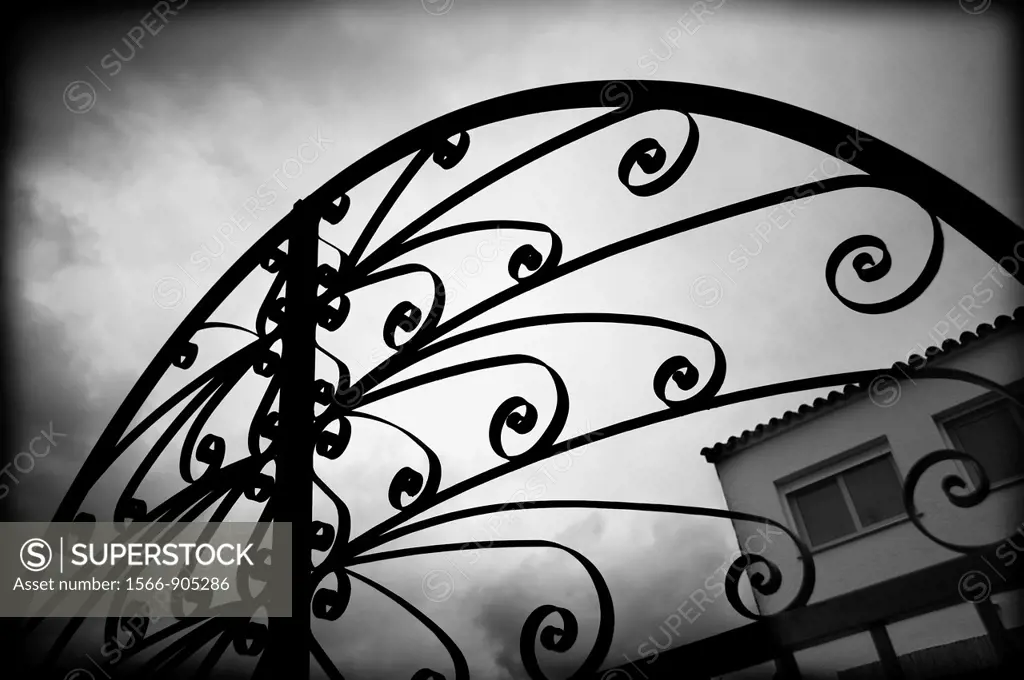 Top of the iron gate wrought iron and the entrance to a home field.