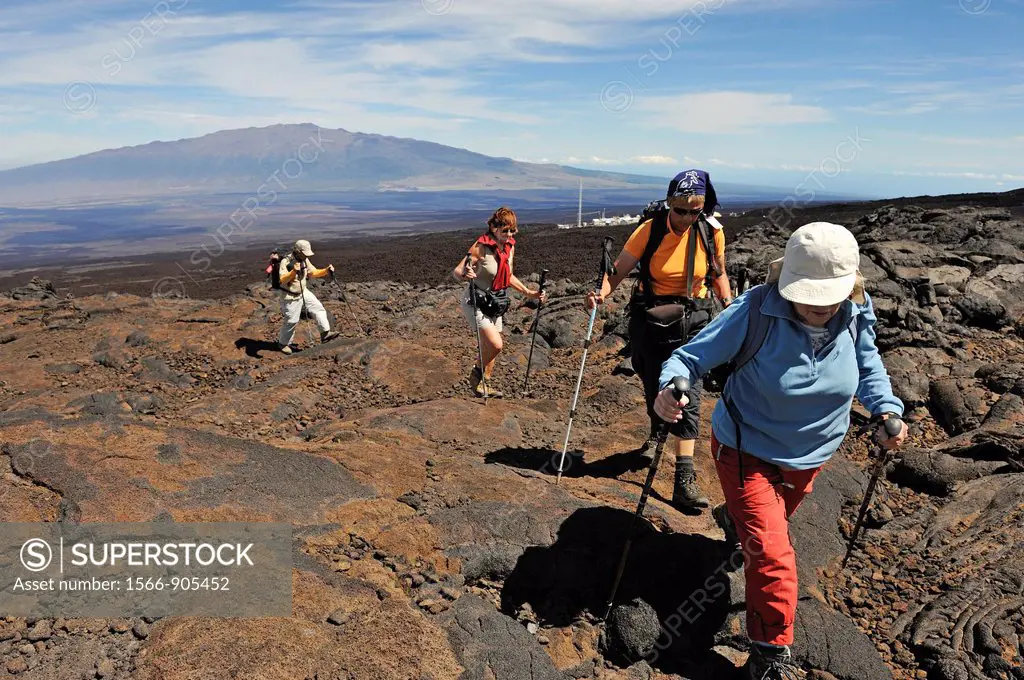 Group of hickers walking on cooled lava, Mauna Loa Volcano Mauna Kea in the background, Big Island, Hawaii Islands, USA