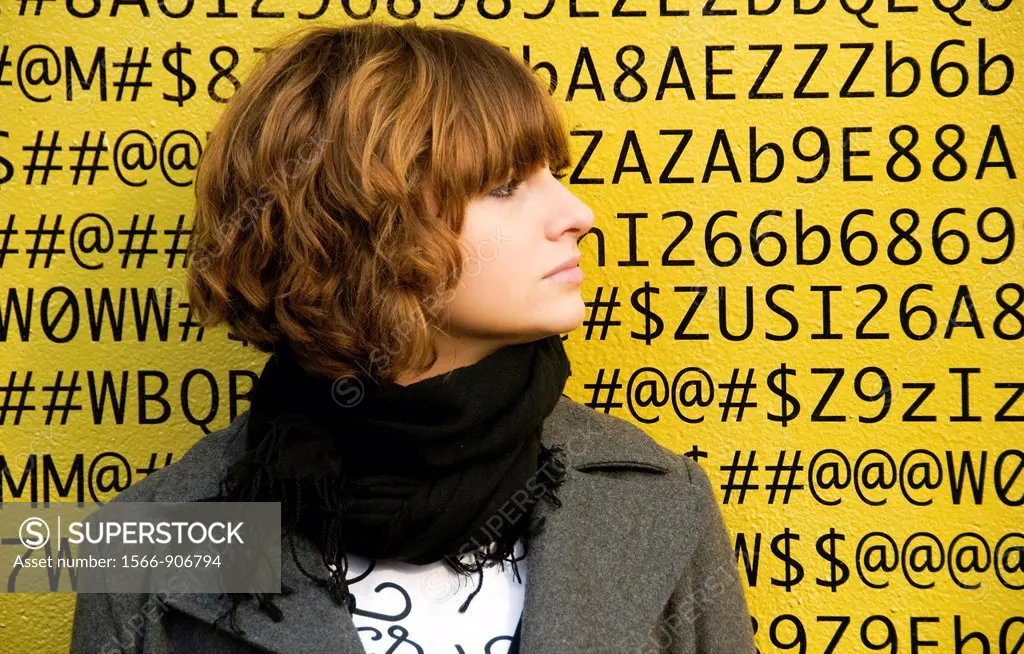A face of young woman in front of numbers, letters, symbols, background is a painted wall of one of buildings in Geneva, Switzerland