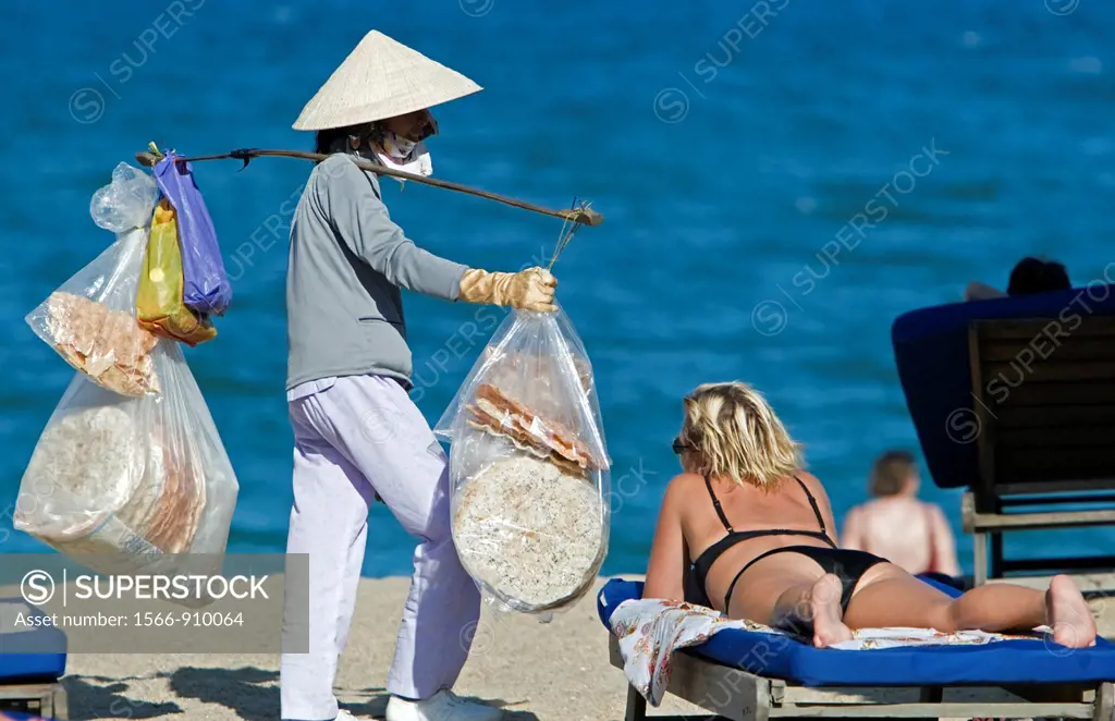 Conical hat woman selling snacks on beach Nha Trang resort Vietnam