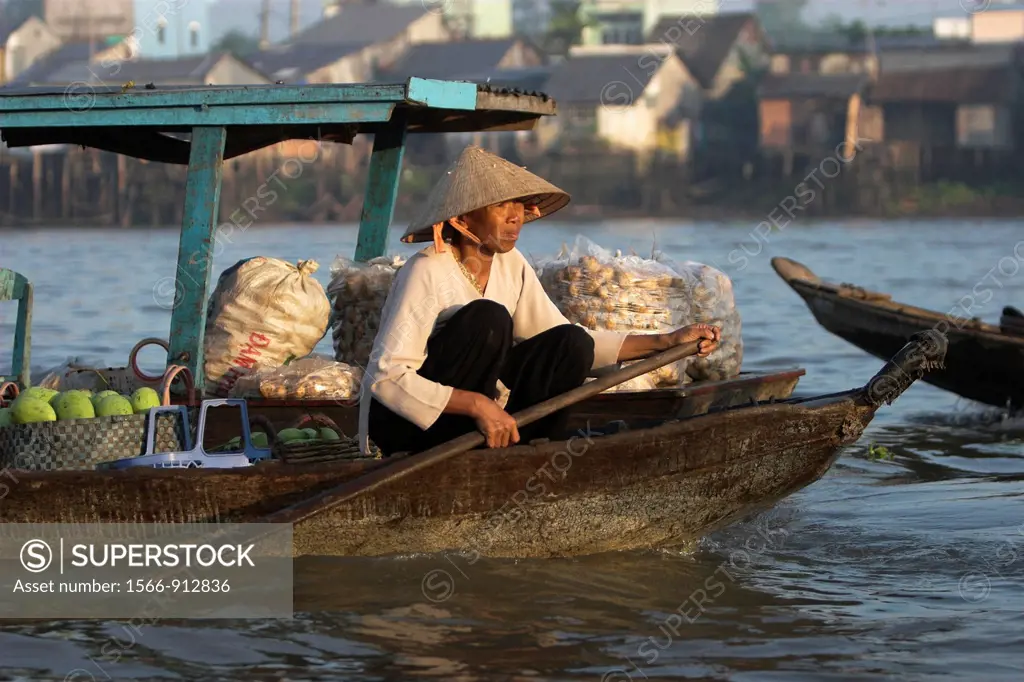 Woman in conical hat paddles her boat of produce at Cai Ran floating market near Can Tho Vietnam