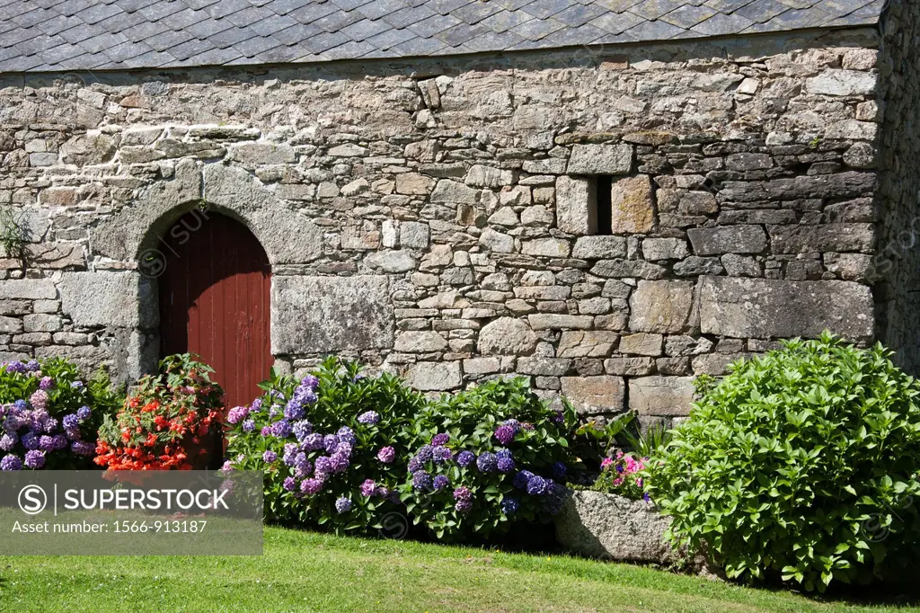 Old stone wall, doors and flower garden, Brittany, France