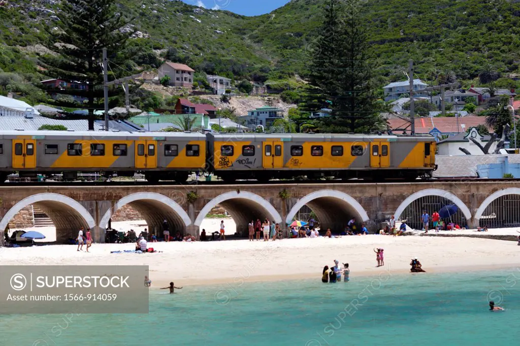 The yellow Metro of Cape Town´s mass transit system crossing a bridge over the beach at Kalk Bay, False Bay near Cape Town, South Africa