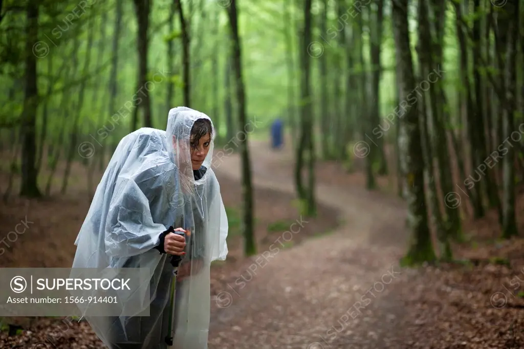 Women in rain coat standing in a forest on the Camino de Santiago near Roncesvalles, Spain