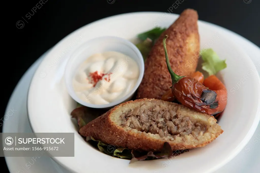 A serving of Kibbeh also kubbeh with Tehina and salad  Kibbeh is meat and spices wrapped in bulgur and deep fried