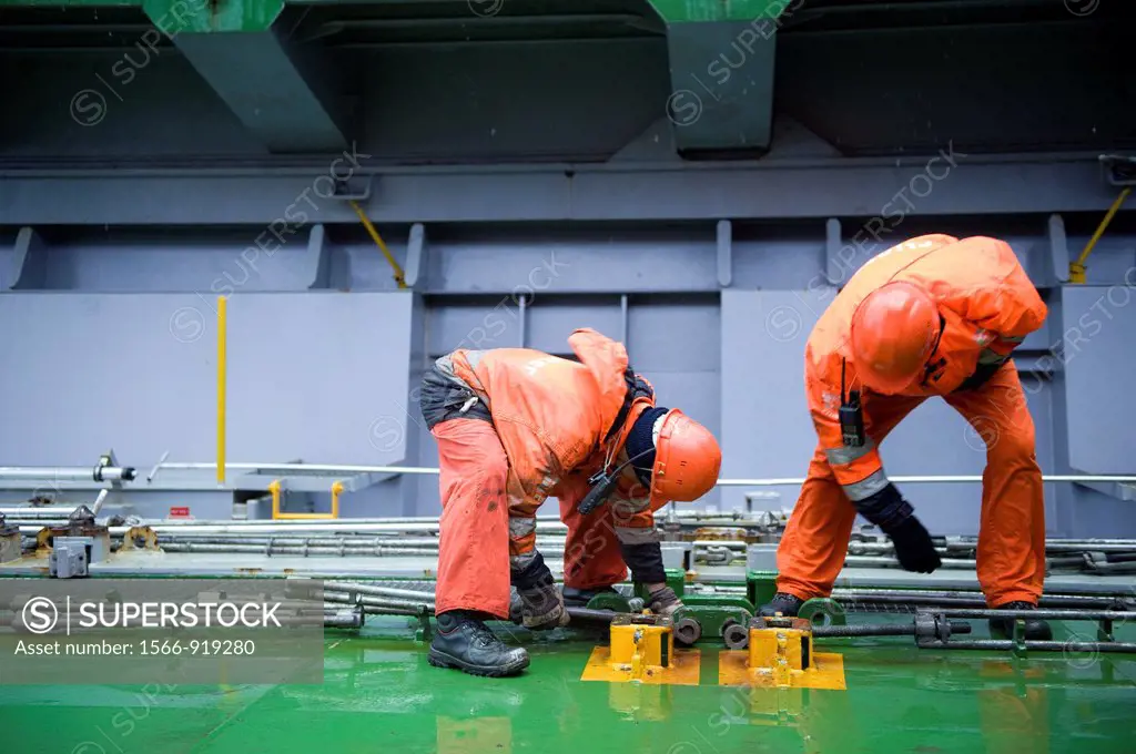 Two ´Able Seamen´ or sailors are preparing the hole and the deck of container-vessel MV Flintercape, for recieving new containers. The Flinetrcape wil...