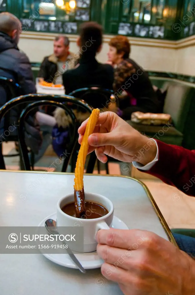 Man having chocolate with churros. Chocolateria San Gines, Madrid, Spain.