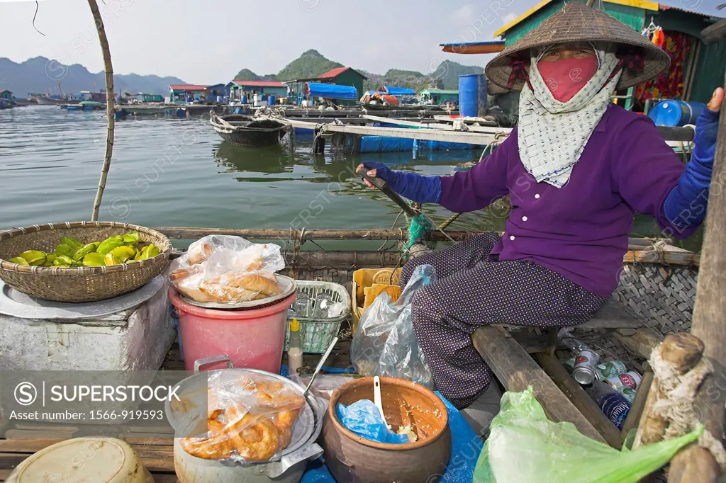 Woman selling bread doughnuts fruit and drinks rows her shop around floating fishing village Cat Ba Town bay north east Vietnam