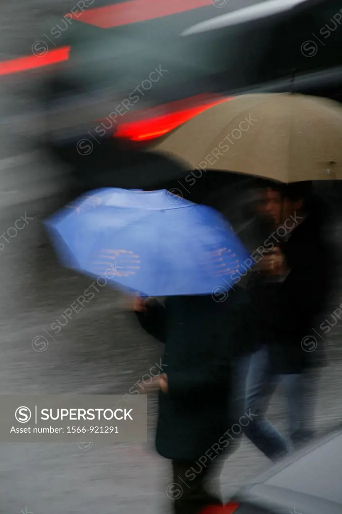 person with umbrella crossing road in rain