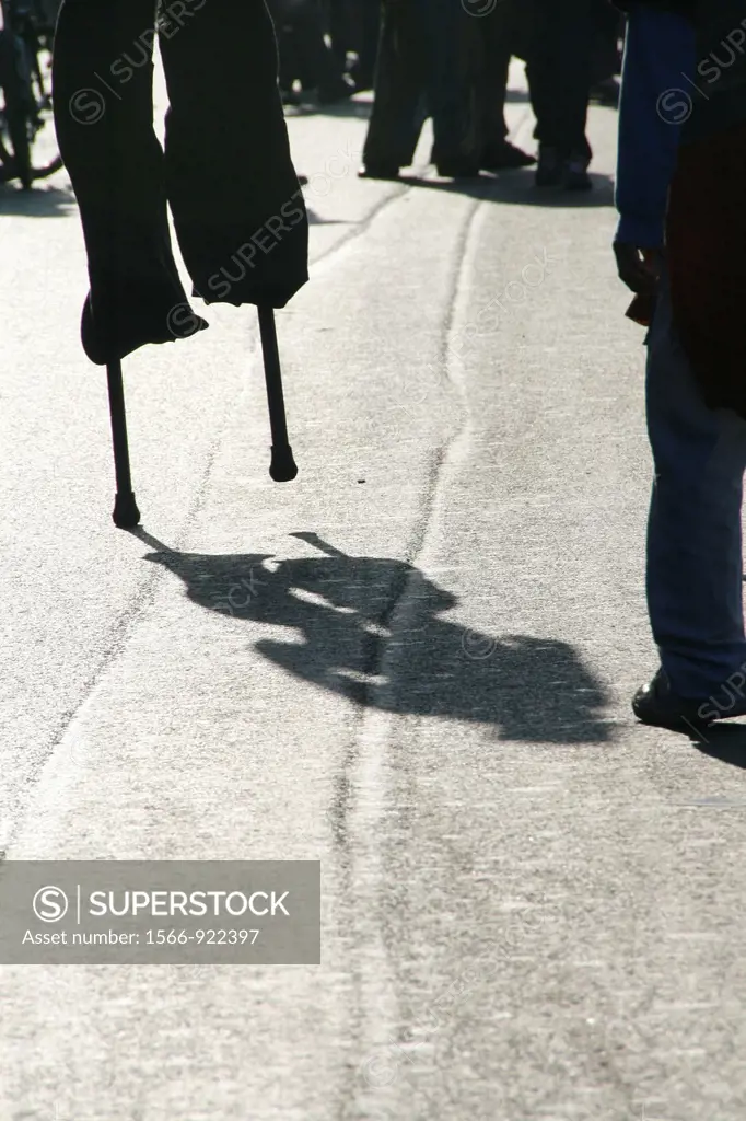 person man walking on stilts in street road in city town