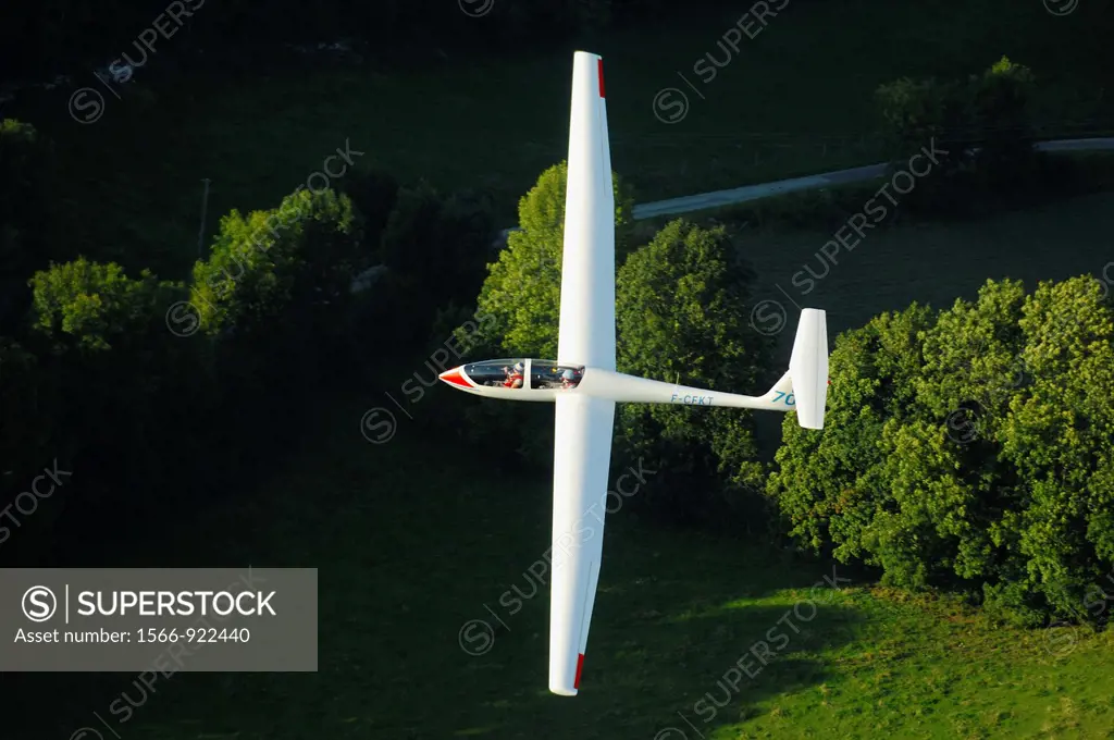 A trainer glider Grob Twin Astir fliying over Alps forest in the evening light, Challes les Eaux, Savoie, France
