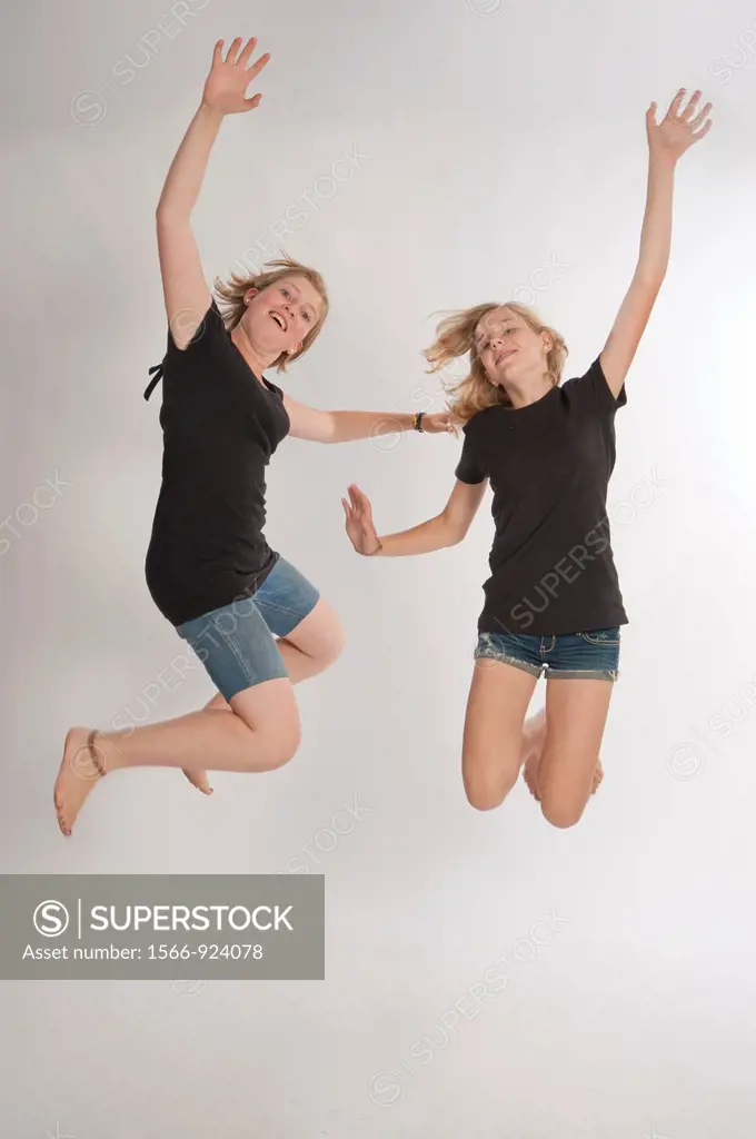 Two teenage girls Central European and jumping during a photo shoot.