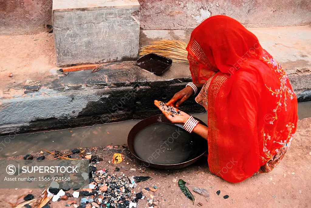 Woman looking for gold dust in a sewer in India