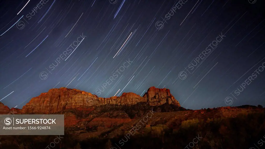 Star trails appear over The Watchman mountain at night at Zion National Park, Utah