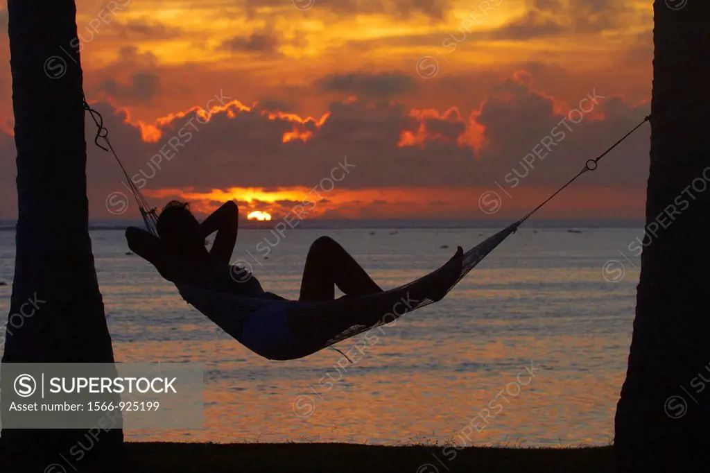 Woman in hammock, and palm trees at sunset, Coral Coast, Viti Levu, Fiji, South Pacific