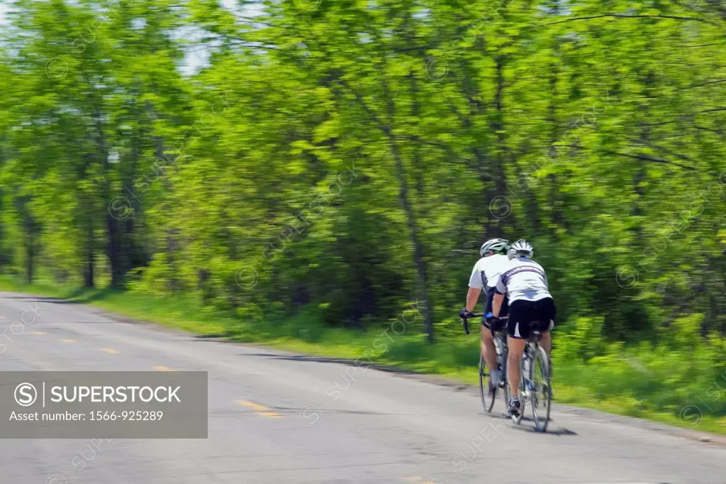 Cyclists in motion on an asphalt road in the countryside, Quebec, Canada