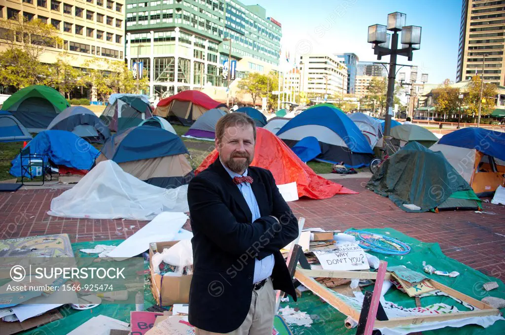 Man stands in jest against occupy movement tents in Baltimore Maryland USA