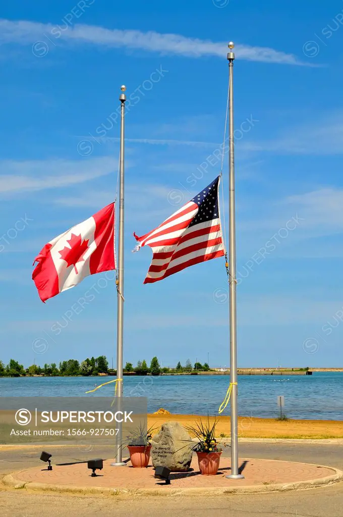 American and Canadian flags fly together at half mast staff
