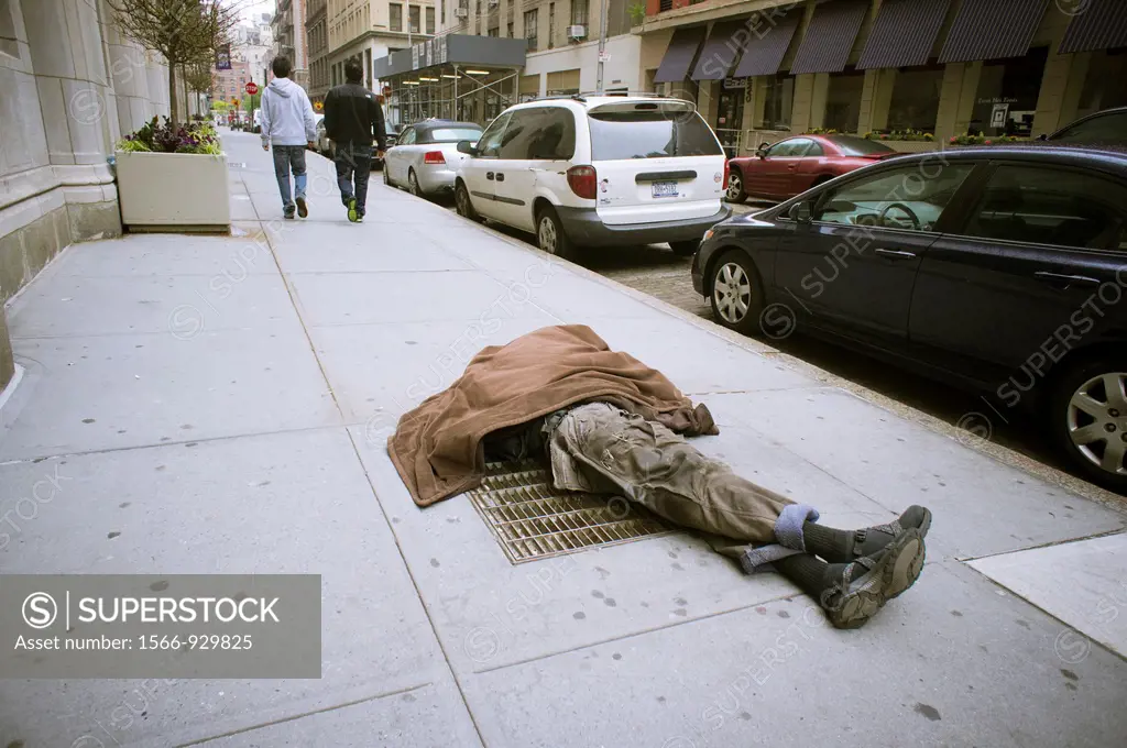 Homeless man sleeping on a vent in the sidewalk in Greenwich Village in New York With the deteriorating economy many worry about the return of crime a...