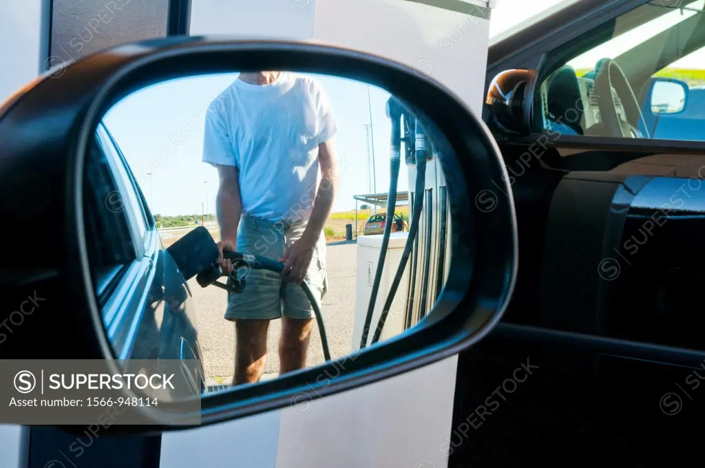 Man holding gas pistol, refuelling at a gas station