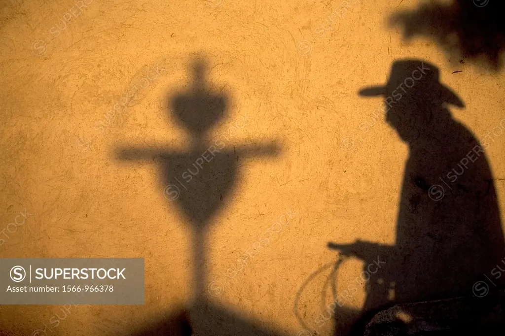 The shadow of a man wearing a hat and cycling is cast with a cross in a wall in San Gregorio Atlapulco cemetery, Xochimilco, Mexico City. The Day of t...