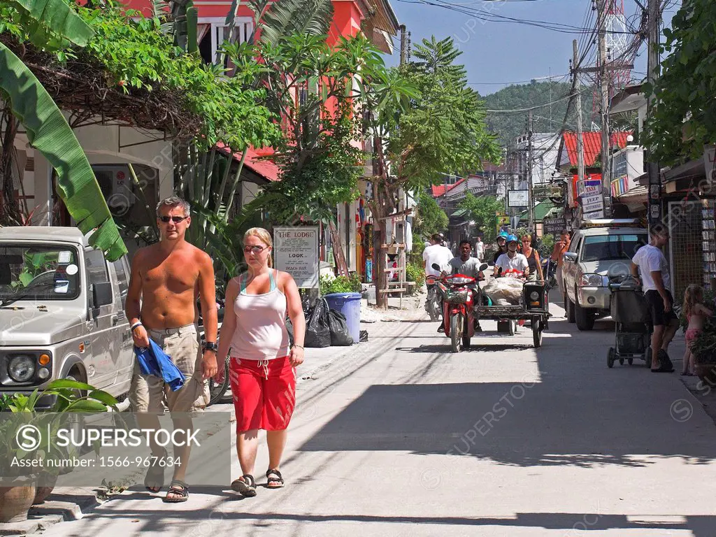 Couple walking on main street lined with shops and restaurants at Bo Phut Beach north Ko Samui island Thailand