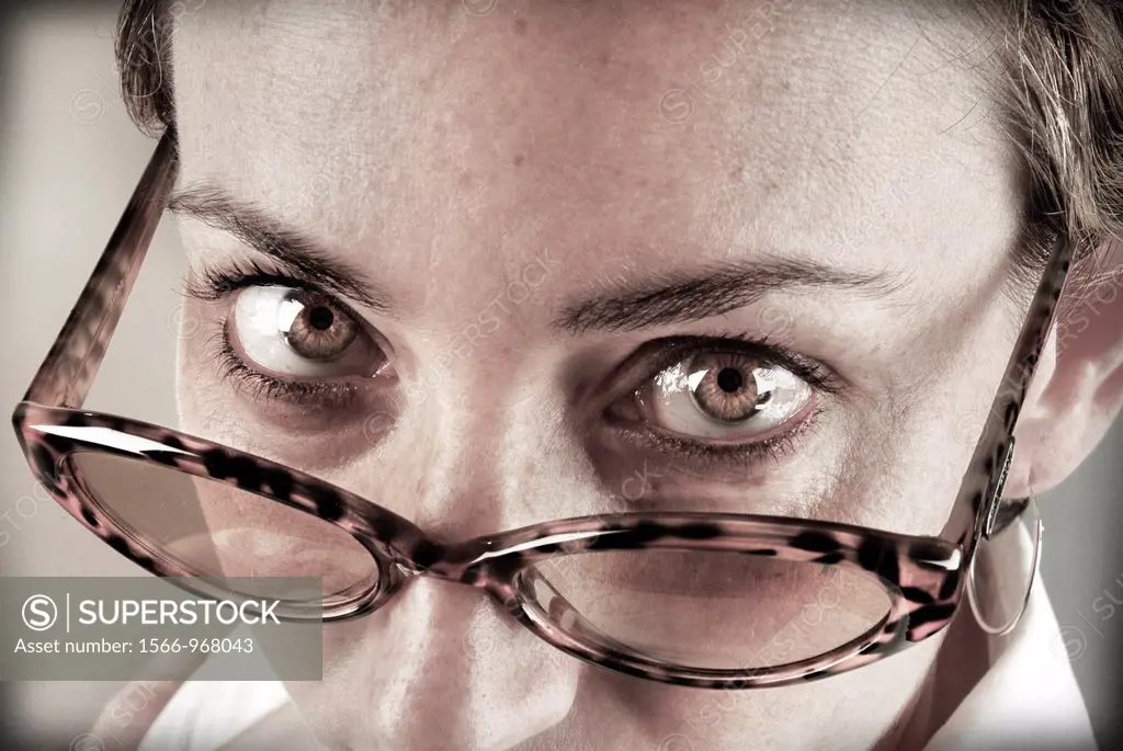 Closeup of young woman staring at the camera above his glasses.
