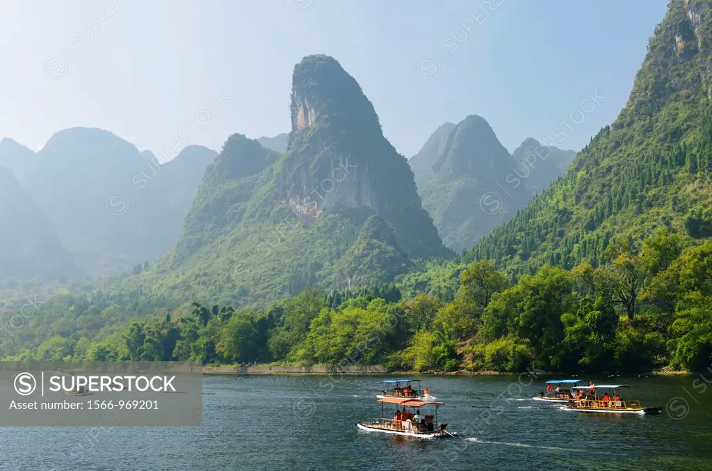 Tour boat rafts on the Li river Guangxi China with pointy karst mountain peaks in the haze
