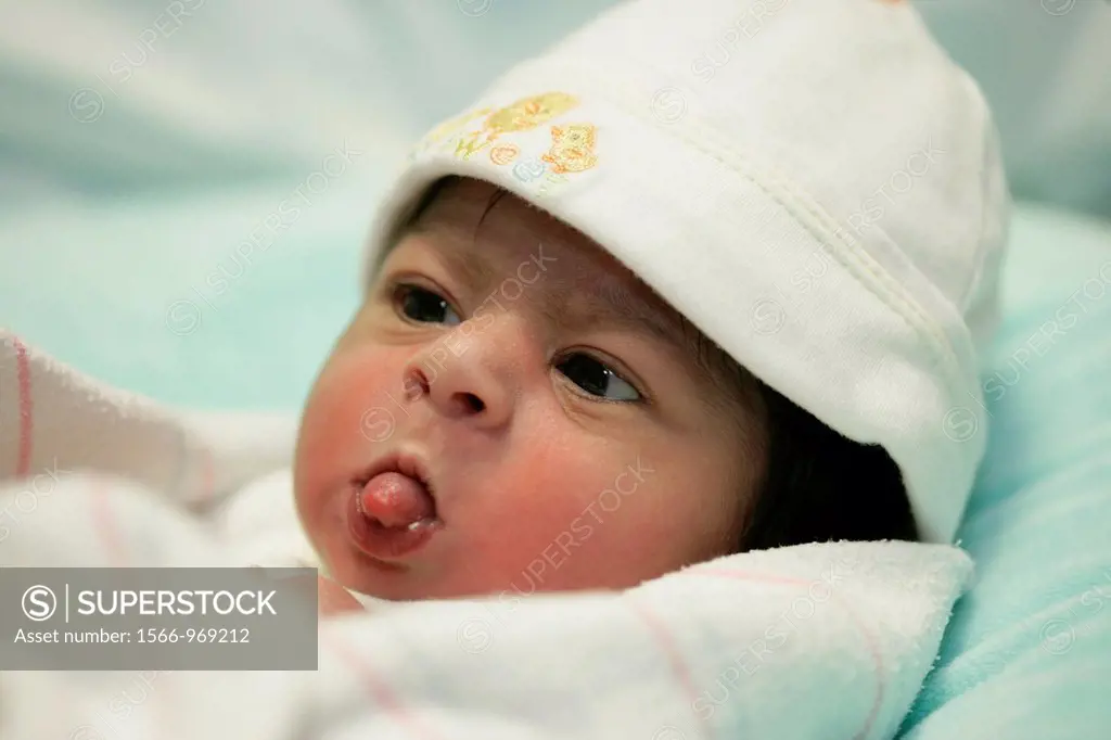 Two day old baby sticks her tongue out in a confident, playful gesture.