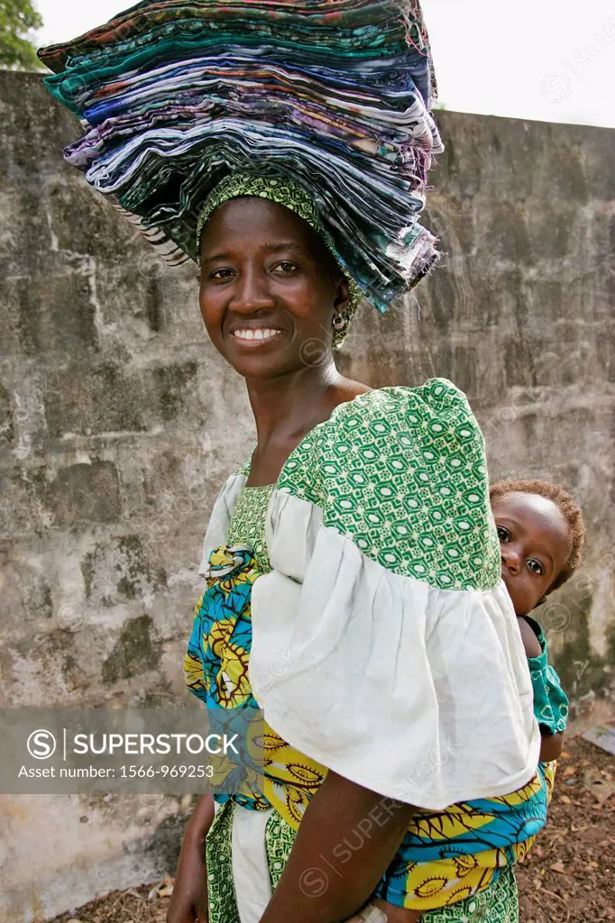 Fula woman in carries folded cloth on head and baby on back Bakau The Gambia