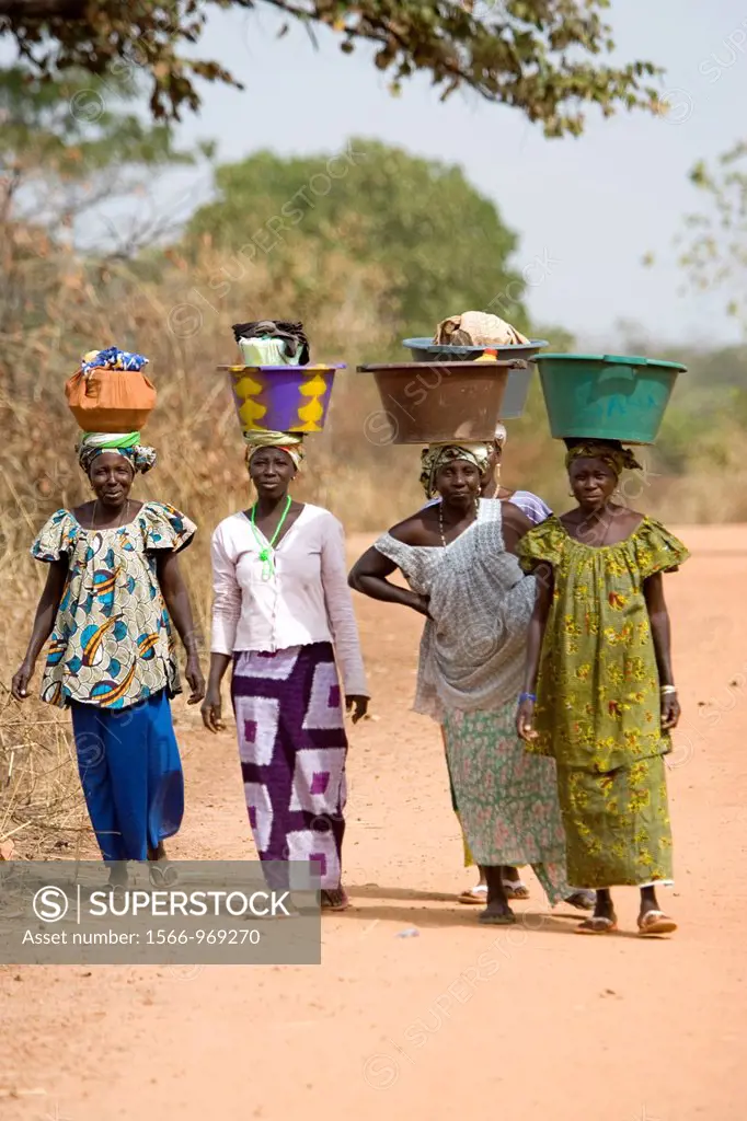 Women carry basins and goods on head bush road The Gambia
