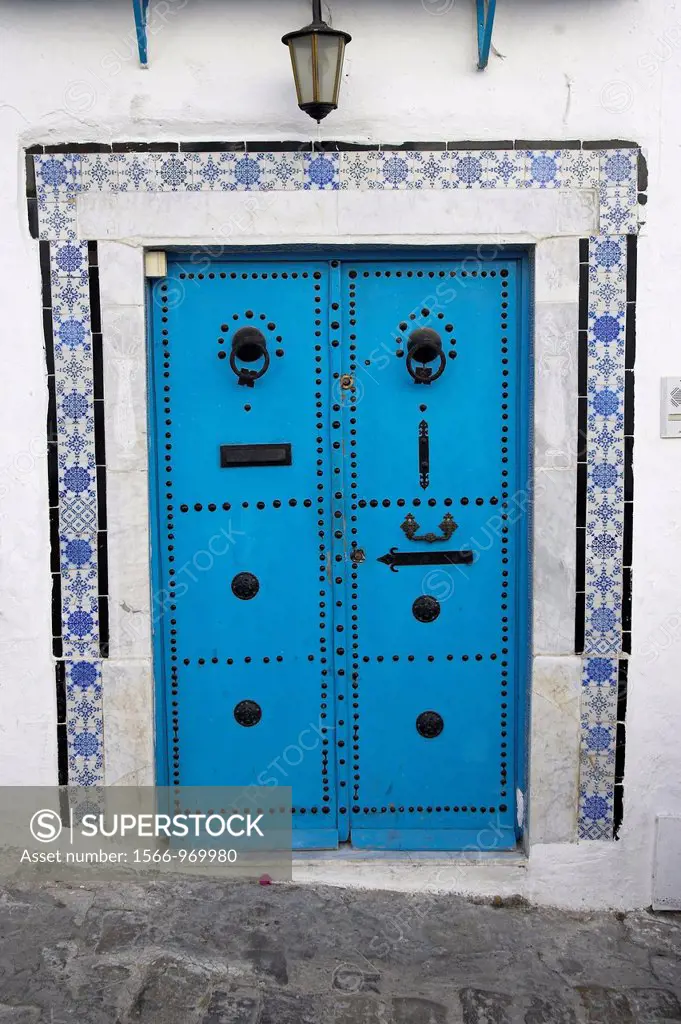 Blue studded door with black knockers and decorated tile surround Sidi Bou Said village Tunisia
