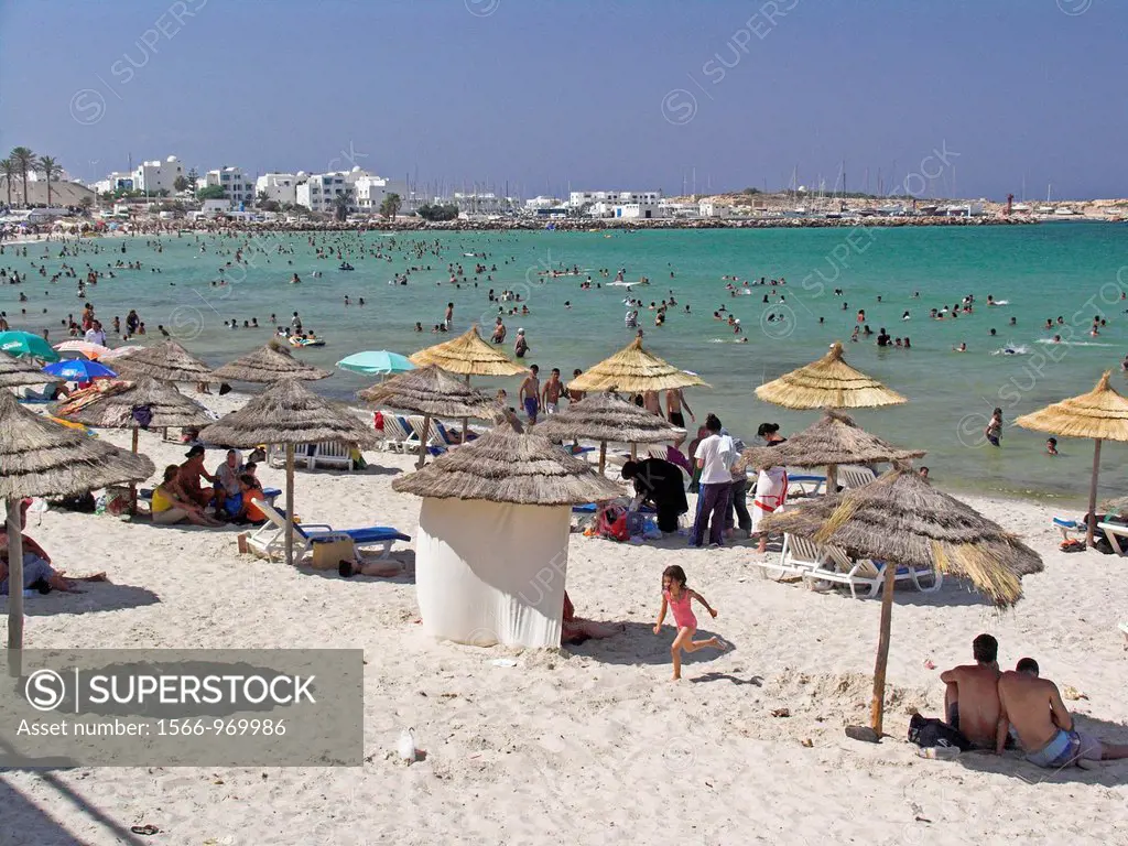 Thatch sunshades line beach holidaymakers cool off Monastir Beach Tunisia