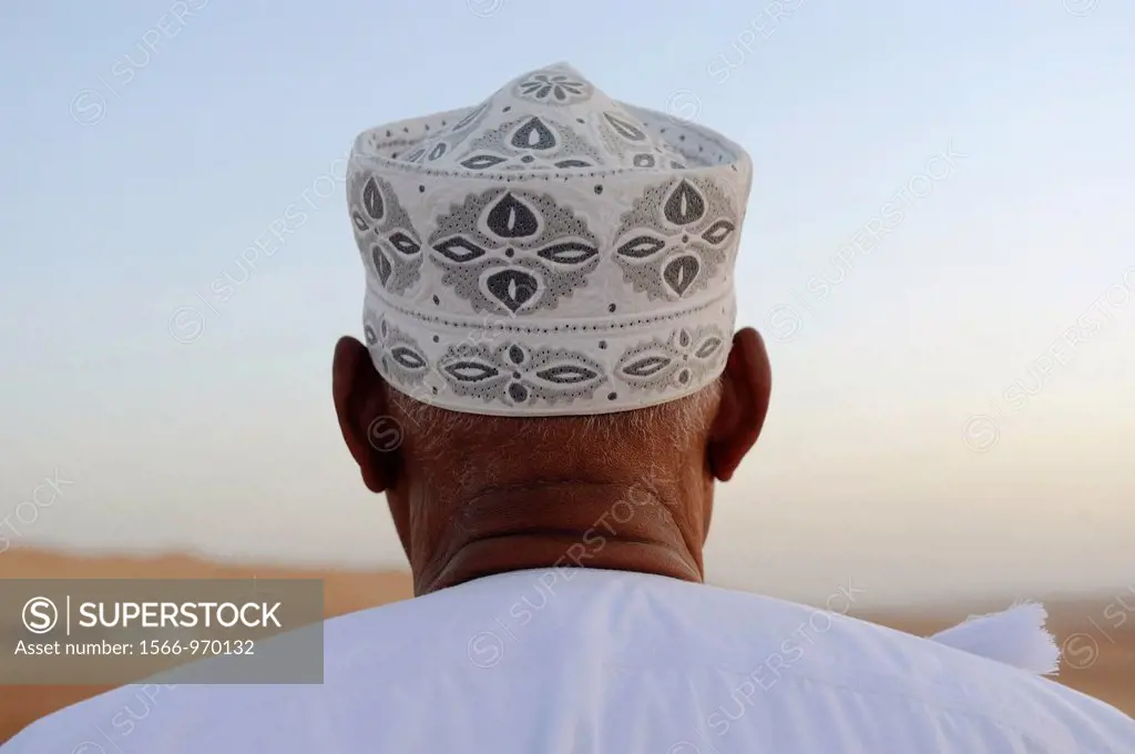 Middle East,Oman, Sharqiyah,Wahiba Sands,man wearing a hat watching the desert