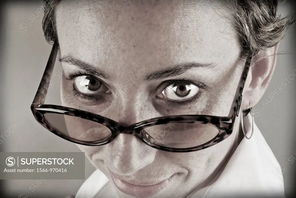 Closeup of young woman staring at the camera above his glasses.