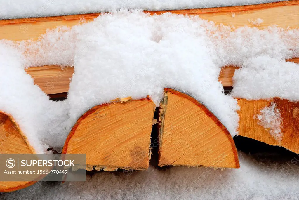 Snow lies on a pile of firewood