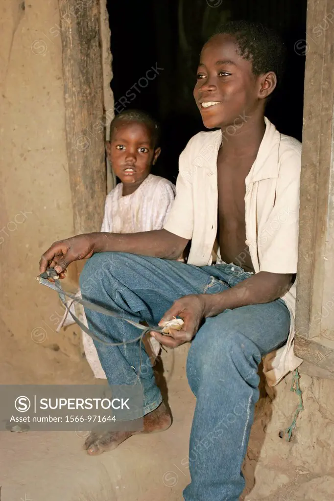 Boy in doorway with catapult Berending village south of The Gambia