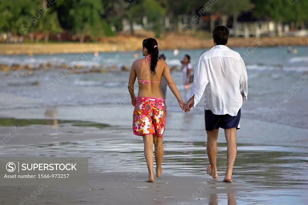 Couple stroll hand in hand on beach Ko Chang Thailand