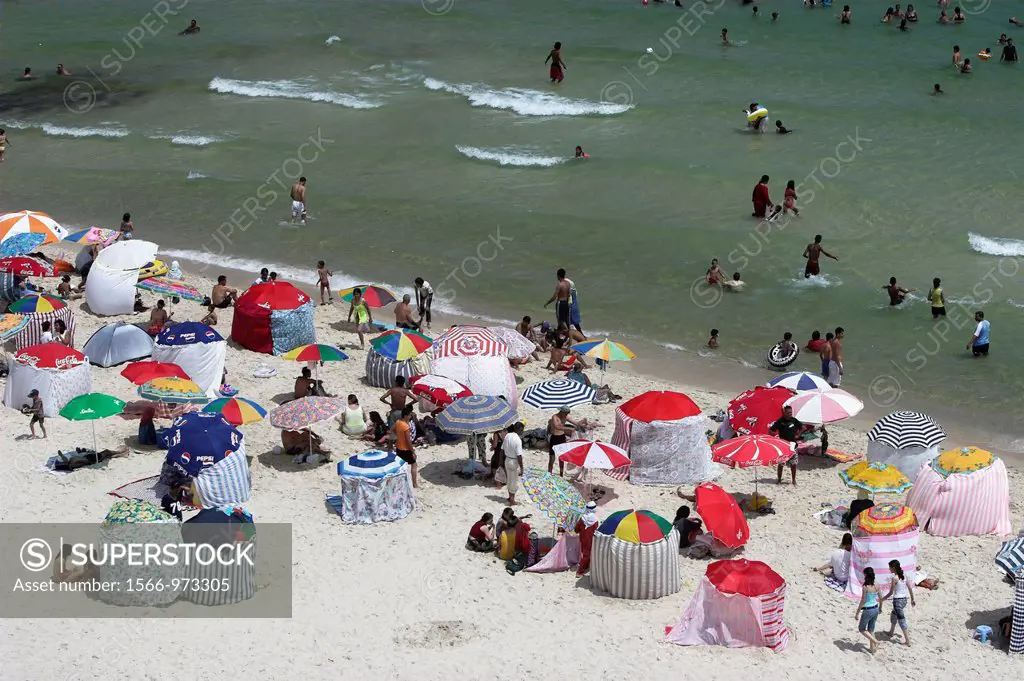 Holidaymakers and coloured umbrellas line Boujaffar Beach Sousse Tunisia