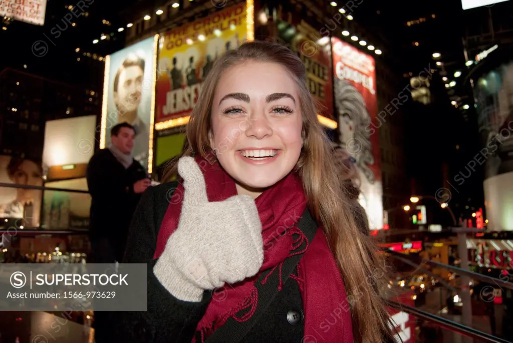A girl smiles, and gives thumbs up, in Times Square, New York city, USA