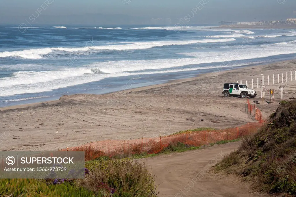San Ysidro, California - A U S  Border Patrol Jeep guards the beach at the Pacific Ocean, just north of the border fence  The hotels of San Diego can ...