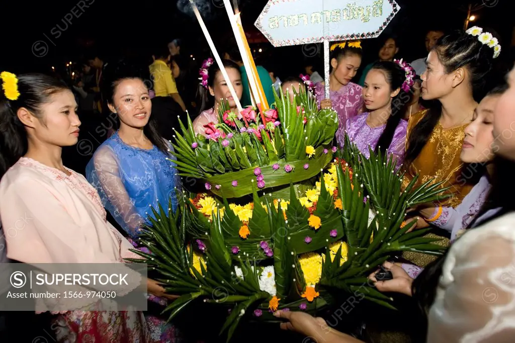 Young women in traditional costume carry a large krathong or float to be lit at Jong Kham Lake Mae Hong Son Thailand
