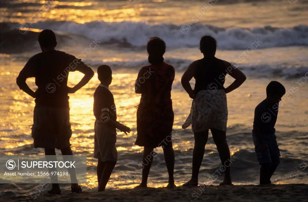 Silhouettes of familly watching sunset on Kalutara beach, Sri Lanka