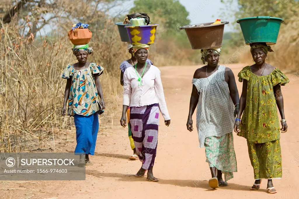 Women carry basins and goods on head bush road The Gambia