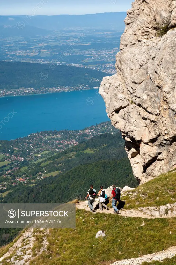 Hikers ascending on a narrow trail to the Tournette refuge in the Bornes Mountains Massif des Bornes above the Lake of Annecy Lac d´Annecy, Annecy, Ha...