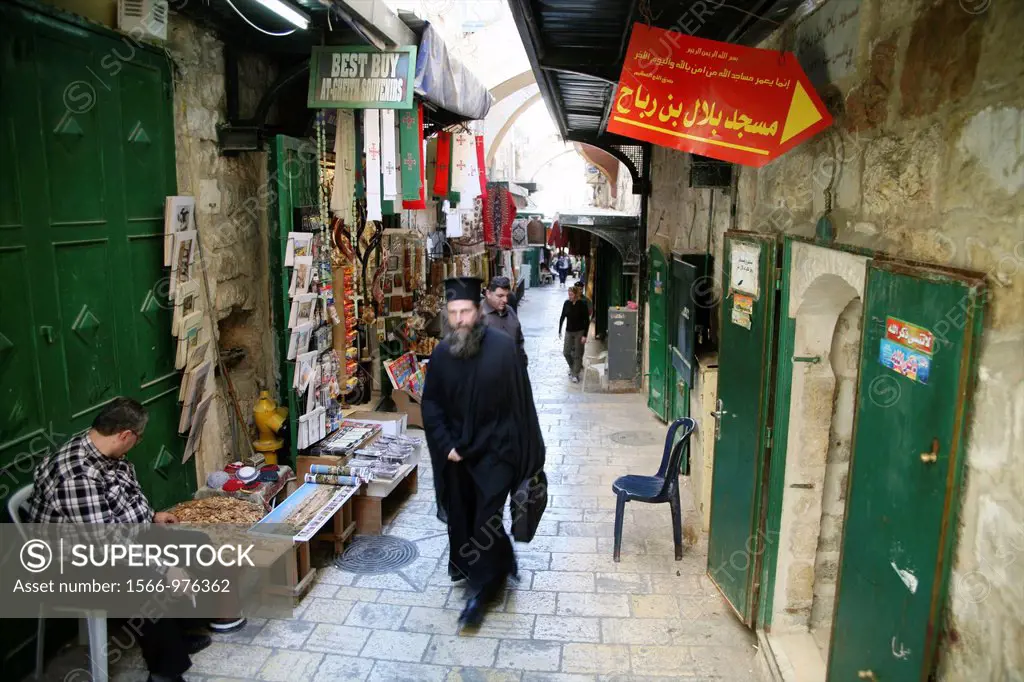 A man in traditional robes walks through a market in the old city section of Jerusalem