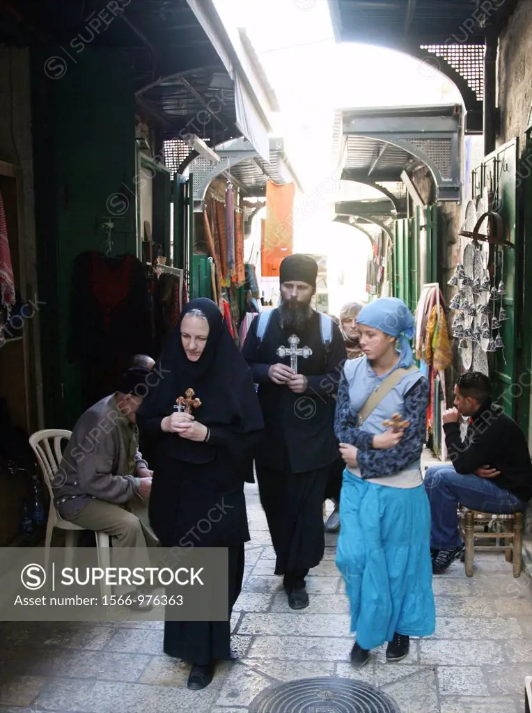 A group holding crosses walks through a market in the old city section of Jerusalem