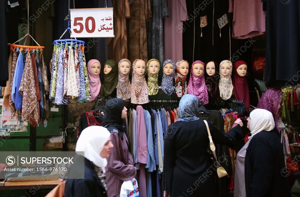 Women shop for clothes in front of a headscarf display at a market in the old city section of Jerusalem
